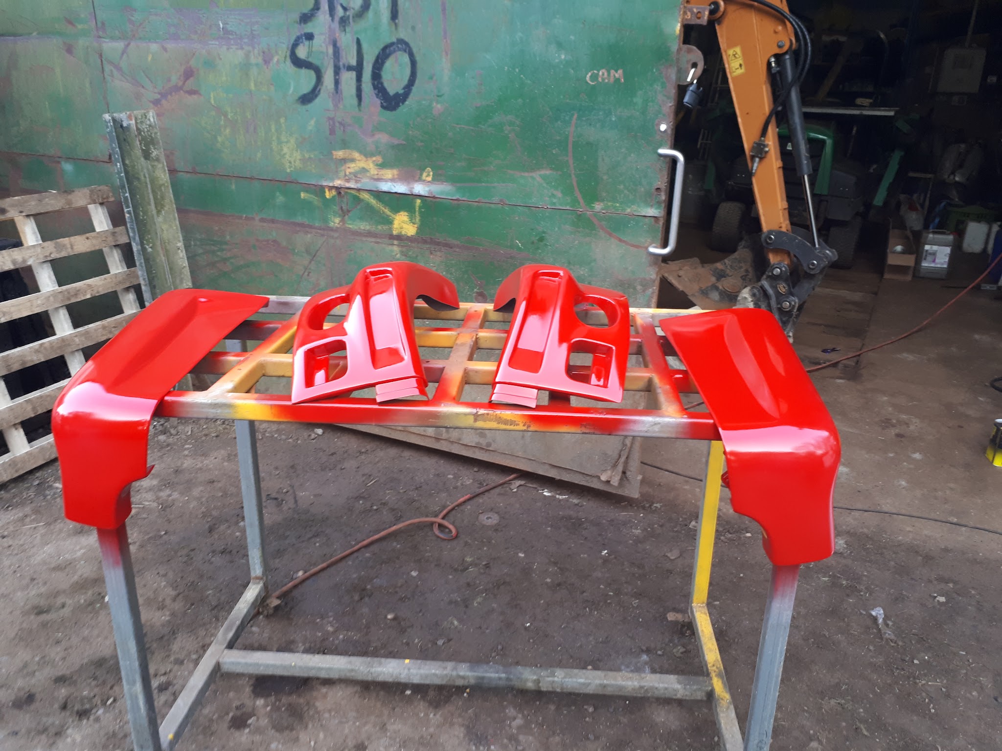 Finished red vehicle panels laid out on a stand at K.A.R.S